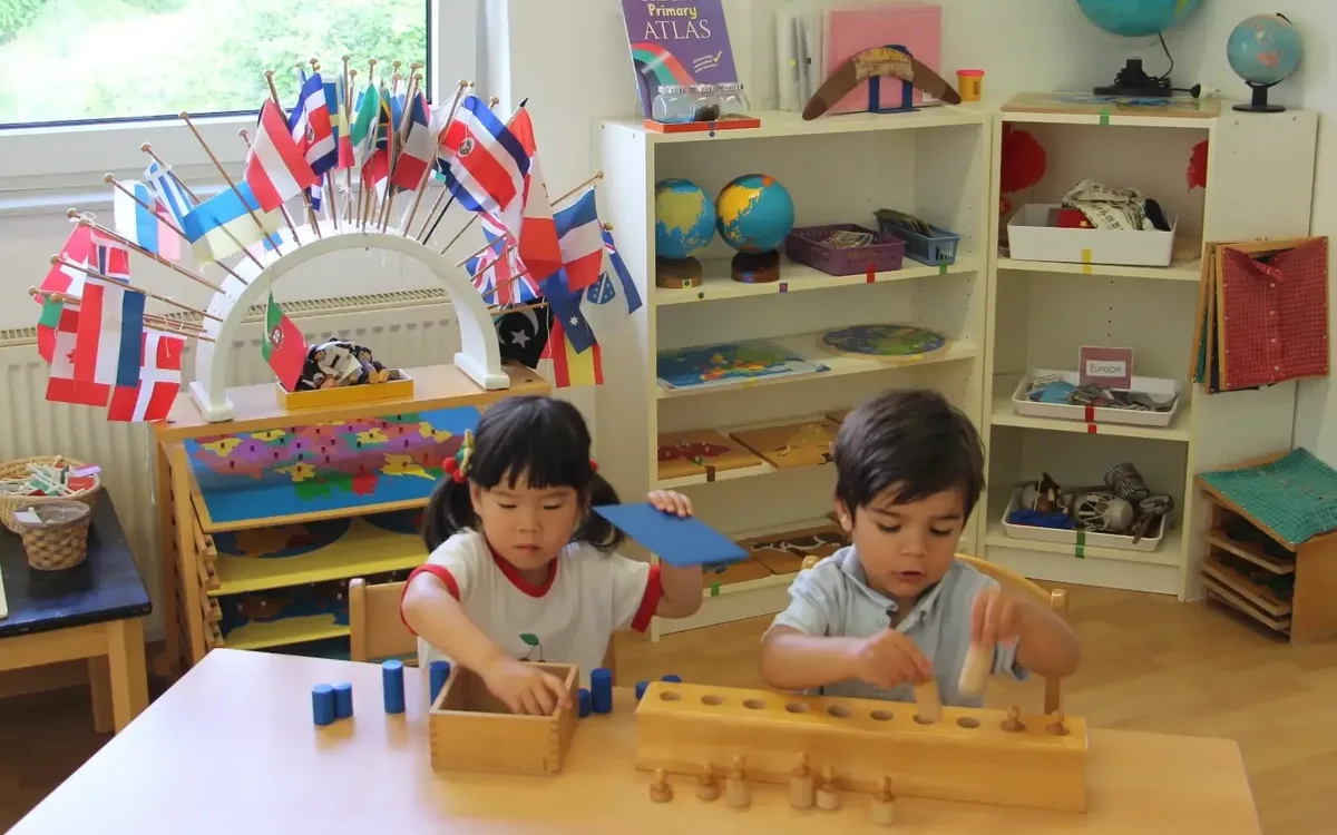 Children exploring international flags and Montessori geography materials in an English-speaking classroom at TIMS near Frankfurt