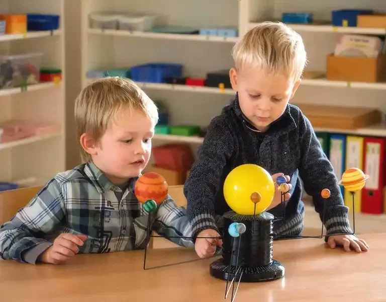 Two kindergarten-age boys exploring a Montessori solar system model at TIMS
