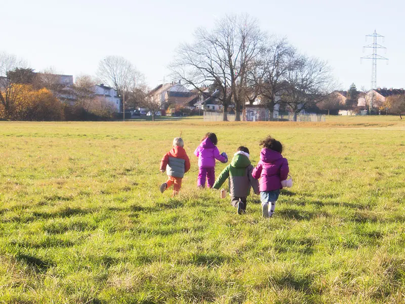 Children running together across a grassy field outdoors