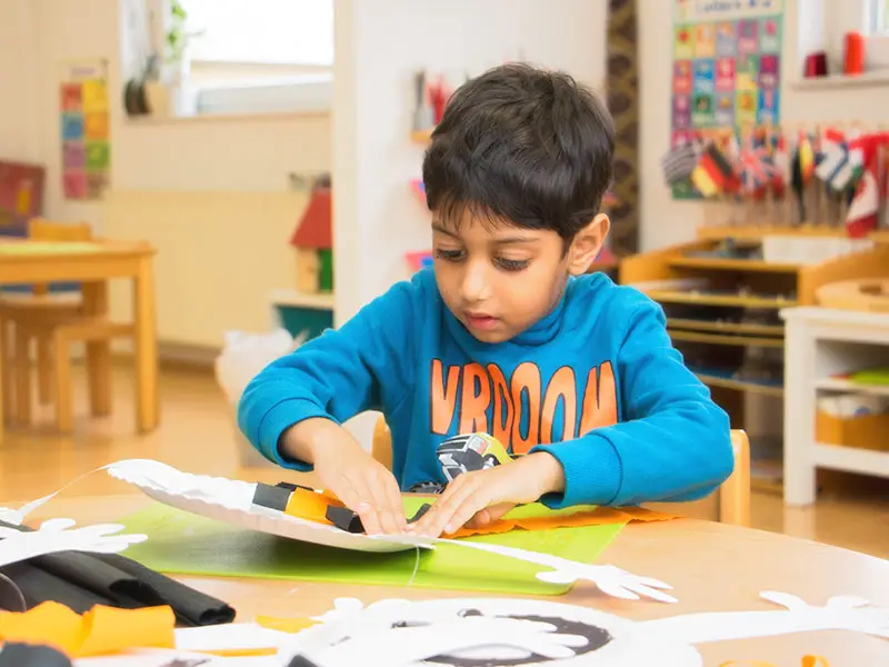 Boy practicing scissor-cutting skills during a classroom craft activity