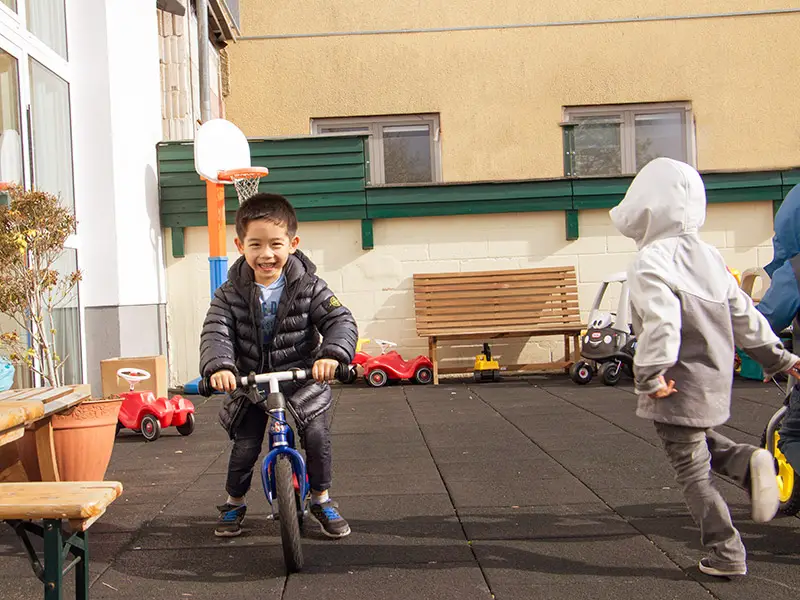 Smiling boy riding a balance bike in the school playground courtyard