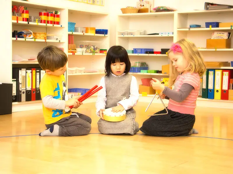 Three children playing musical instruments together in a circle